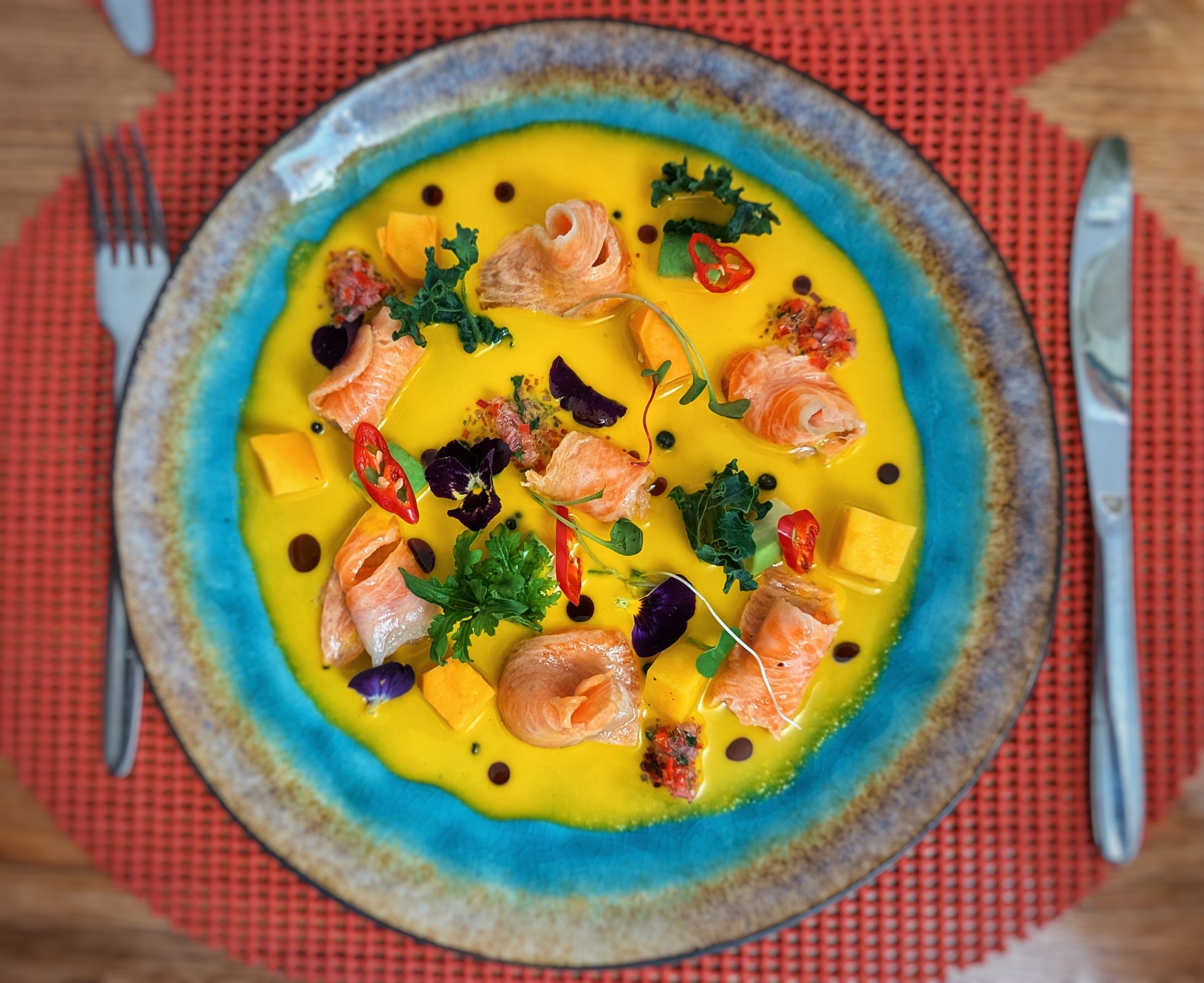 Ceviche met mango en bloemen op een blauw bord